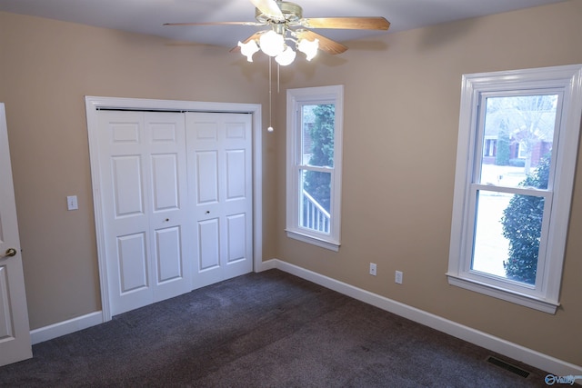 unfurnished bedroom with a closet, dark carpet, and ceiling fan