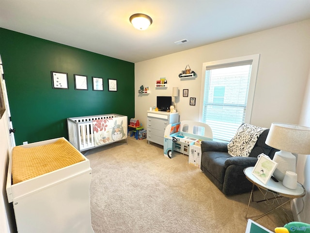 carpeted bedroom with visible vents and a crib