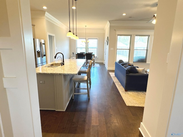 kitchen featuring a sink, ornamental molding, a breakfast bar, and stainless steel refrigerator with ice dispenser