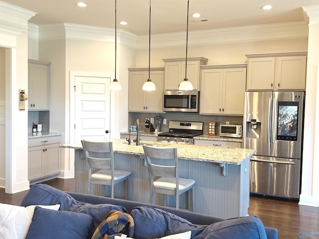 kitchen featuring appliances with stainless steel finishes, a breakfast bar area, open floor plan, tasteful backsplash, and ornamental molding