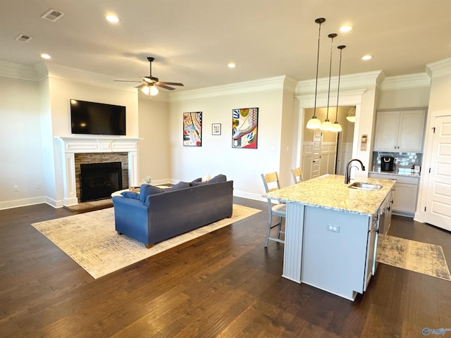 kitchen featuring visible vents, a sink, crown molding, and an island with sink
