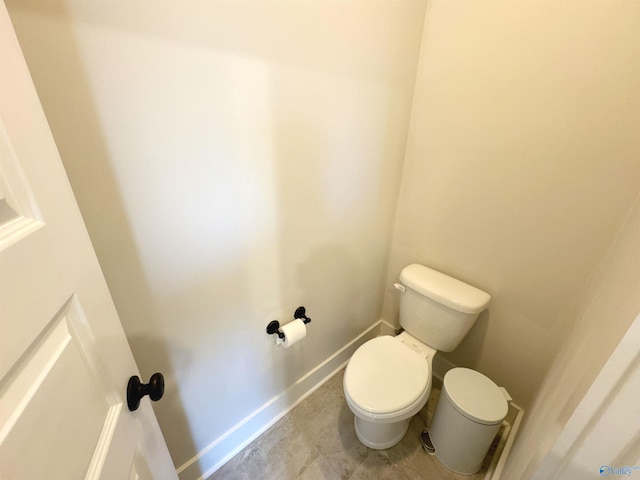 bathroom with baseboards, tile patterned flooring, and toilet