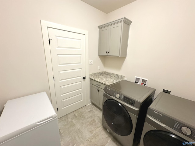 clothes washing area featuring independent washer and dryer and cabinet space