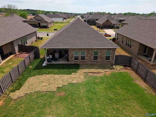 back of property with a residential view, a patio area, brick siding, a yard, and a shingled roof