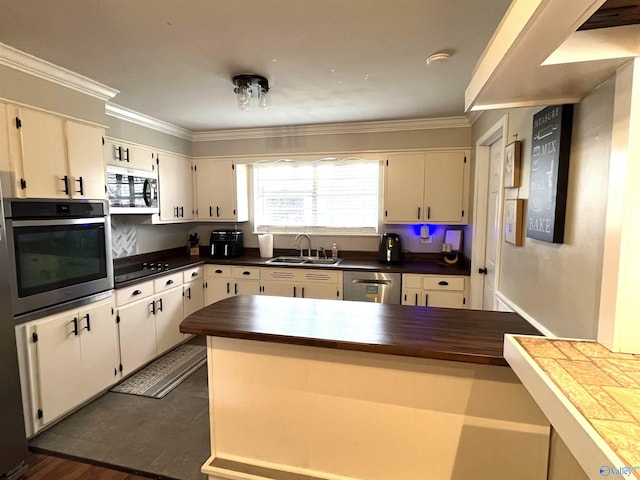 kitchen featuring stainless steel appliances, ornamental molding, a sink, and white cabinetry