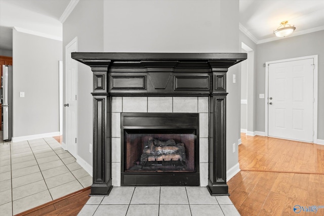 details featuring stainless steel refrigerator, a tile fireplace, ornamental molding, and hardwood / wood-style flooring