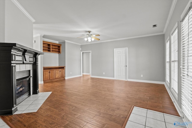 unfurnished living room featuring a fireplace, light hardwood / wood-style floors, ceiling fan, and crown molding