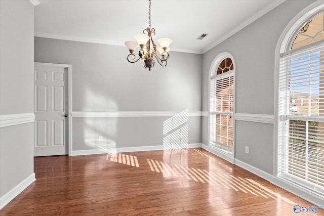 spare room featuring ornamental molding, an inviting chandelier, and dark wood-type flooring