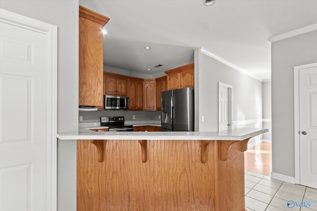 kitchen featuring a breakfast bar, crown molding, light tile patterned flooring, kitchen peninsula, and stainless steel appliances