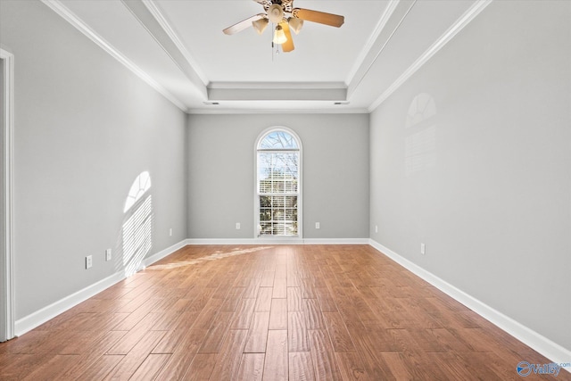 unfurnished room featuring a raised ceiling, crown molding, hardwood / wood-style floors, and ceiling fan