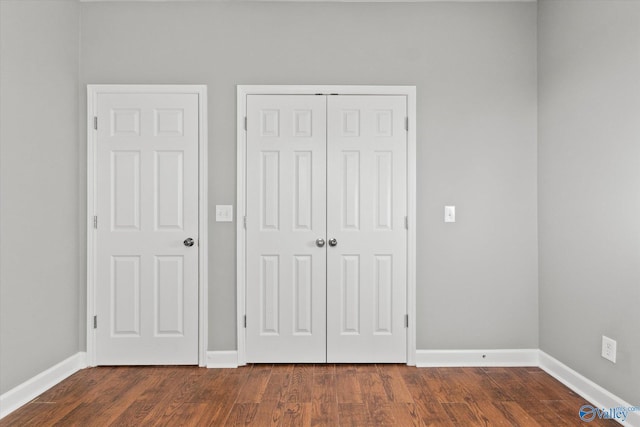 unfurnished bedroom featuring a closet and dark hardwood / wood-style flooring