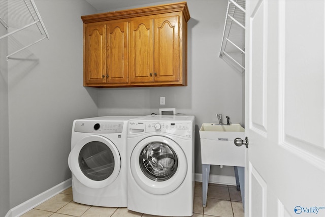 laundry area featuring washer and dryer, light tile patterned flooring, and cabinets