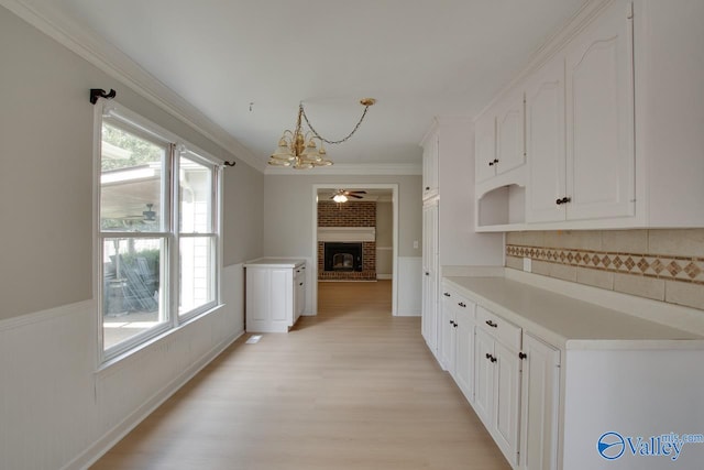 kitchen featuring white cabinets, light wood-type flooring, plenty of natural light, and pendant lighting