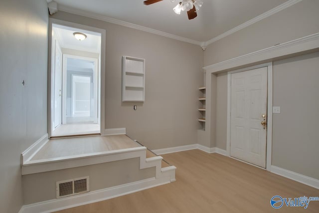 foyer entrance with wood-type flooring, ceiling fan, and crown molding