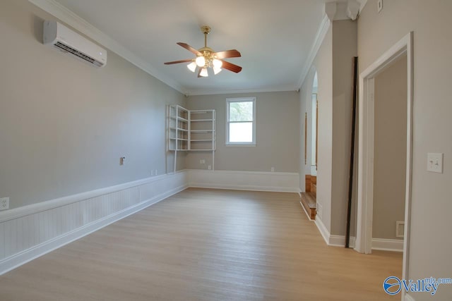 empty room with ornamental molding, light hardwood / wood-style flooring, ceiling fan, and a wall mounted air conditioner