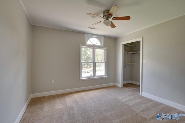 unfurnished bedroom with light colored carpet, ceiling fan, crown molding, and a closet