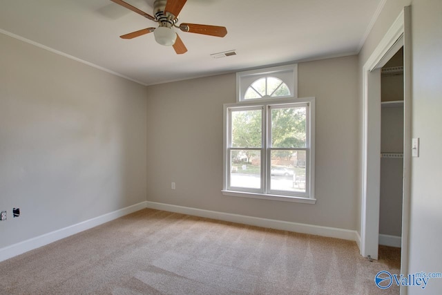 spare room featuring light colored carpet, ceiling fan, and crown molding