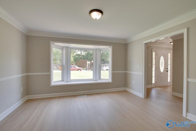 unfurnished room featuring ornamental molding and light hardwood / wood-style flooring