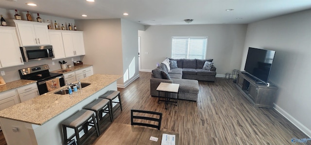 kitchen with a kitchen breakfast bar, appliances with stainless steel finishes, white cabinets, and a kitchen island with sink