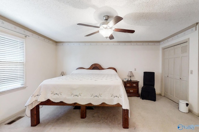 carpeted bedroom with a closet, ceiling fan, and a textured ceiling