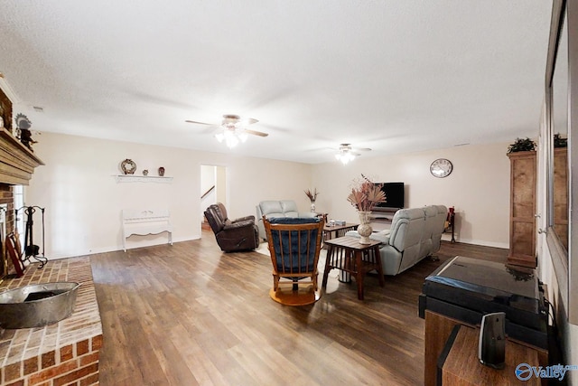 living room with a textured ceiling, a fireplace, ceiling fan, and hardwood / wood-style flooring