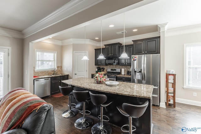 kitchen with sink, a breakfast bar, appliances with stainless steel finishes, a center island, and decorative light fixtures