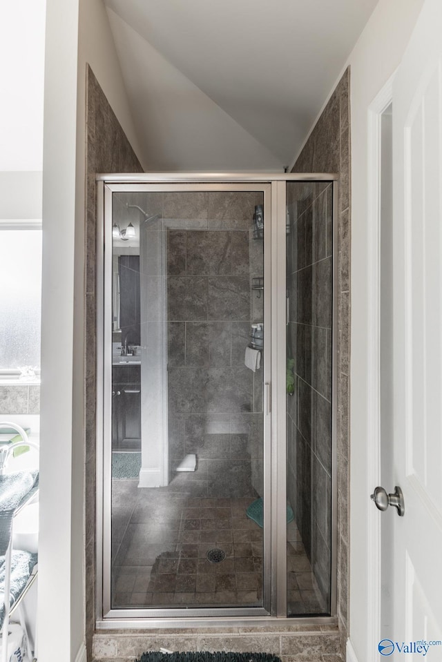 bathroom featuring a shower with shower door and vaulted ceiling