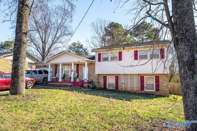 split level home with a porch, a front yard, and brick siding