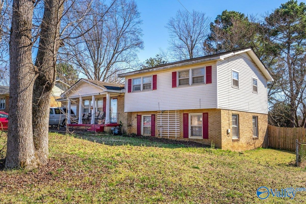 tri-level home with fence, a front lawn, and brick siding