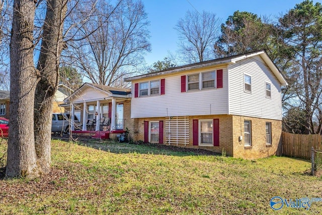 tri-level home with fence, a front lawn, and brick siding