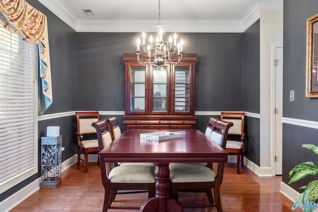 dining space featuring an inviting chandelier, crown molding, and wood-type flooring