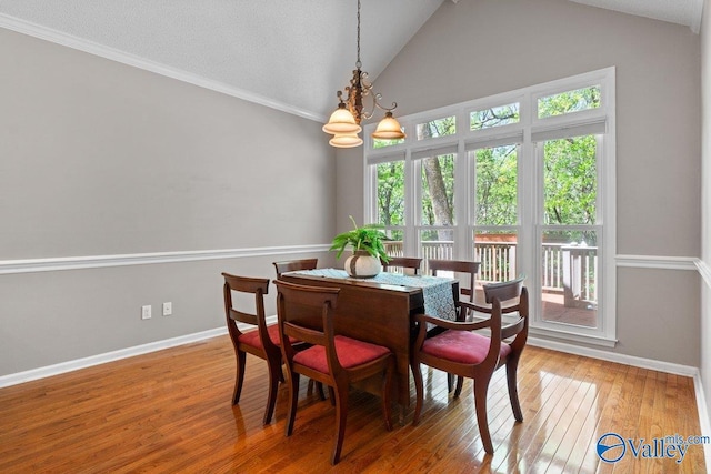 dining room with hardwood / wood-style floors, baseboards, ornamental molding, and an inviting chandelier