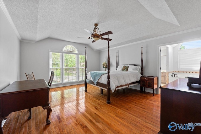 bedroom featuring light wood finished floors, a textured ceiling, lofted ceiling, ceiling fan, and crown molding