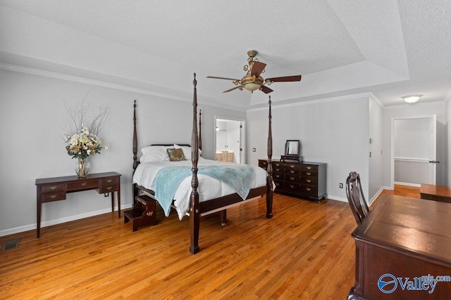 bedroom featuring crown molding, a textured ceiling, light wood finished floors, and baseboards