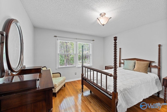 bedroom with baseboards, a textured ceiling, and light wood finished floors