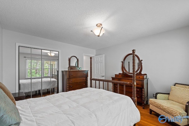 bedroom with a textured ceiling, wood finished floors, and a closet