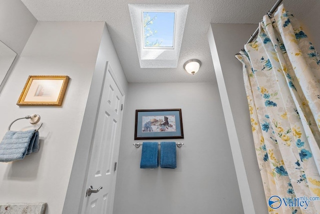 bathroom with a skylight, a shower with curtain, and a textured ceiling
