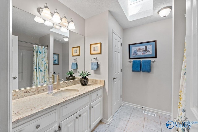 bathroom with a skylight, vanity, baseboards, tile patterned flooring, and visible vents