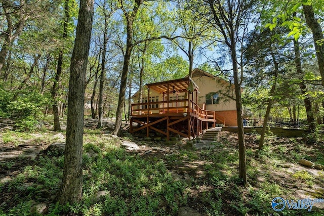 rear view of property featuring stairs, stucco siding, and a deck