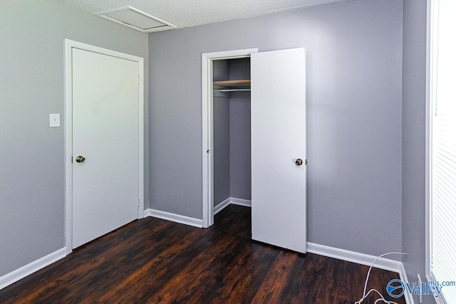 unfurnished bedroom featuring a closet, a textured ceiling, and dark wood-type flooring