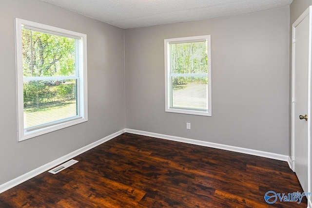 unfurnished room with a textured ceiling, a healthy amount of sunlight, and dark hardwood / wood-style flooring