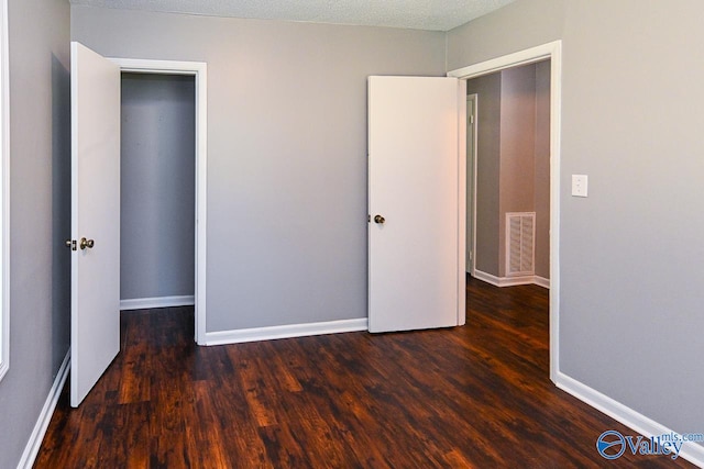 unfurnished bedroom featuring a textured ceiling and dark hardwood / wood-style floors