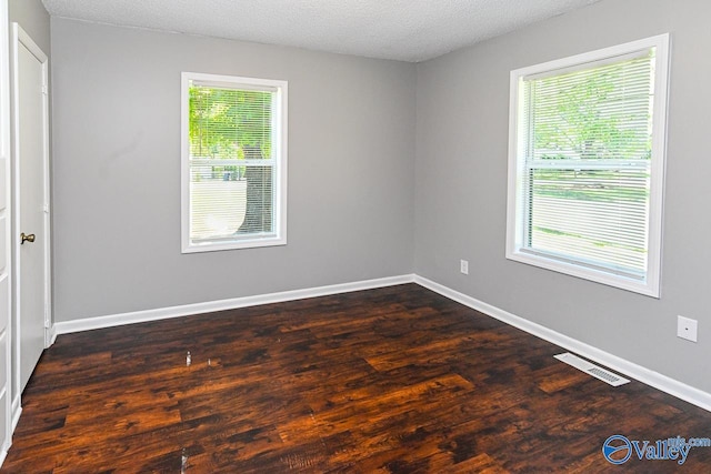 spare room featuring a textured ceiling and dark hardwood / wood-style floors