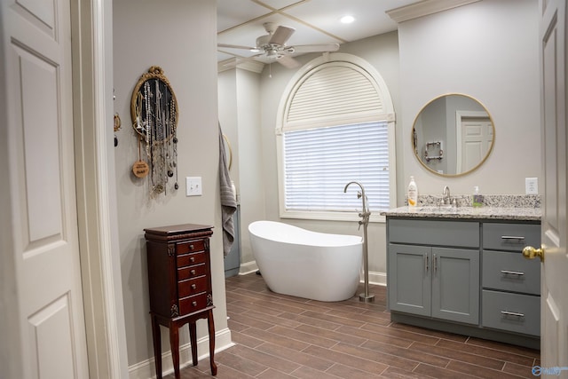 bathroom featuring a tub, ceiling fan, vanity, wood-type flooring, and crown molding