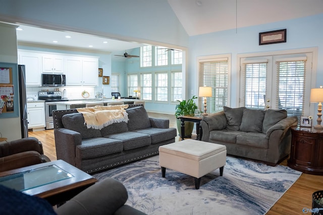 living room with ceiling fan, light hardwood / wood-style flooring, and high vaulted ceiling