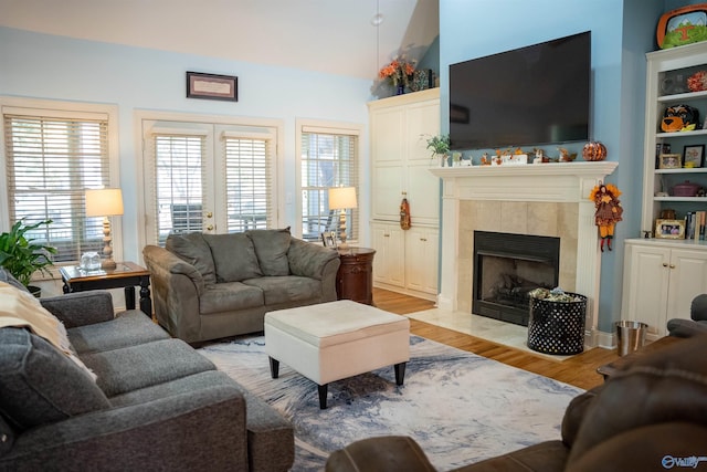 living room featuring vaulted ceiling, light wood-type flooring, and a tiled fireplace