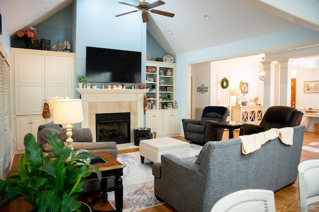 living room featuring high vaulted ceiling, a fireplace, ceiling fan, and light wood-type flooring