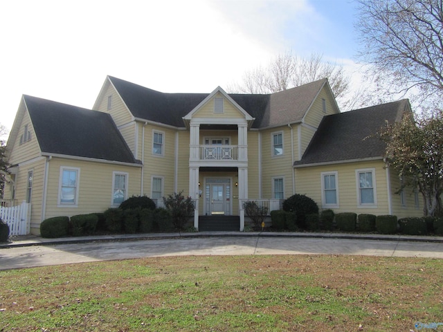 view of front of property featuring a balcony and a front lawn