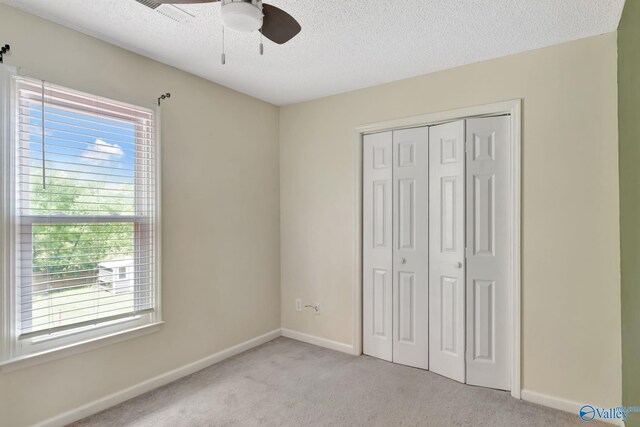 133 Raccoon Trce, Huntsville, AL 35806 - unfurnished bedroom featuring light colored carpet, multiple windows, a textured ceiling, a closet, and ceiling fan