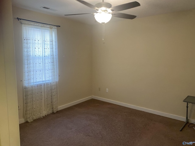 unfurnished room featuring ceiling fan, a healthy amount of sunlight, and dark carpet